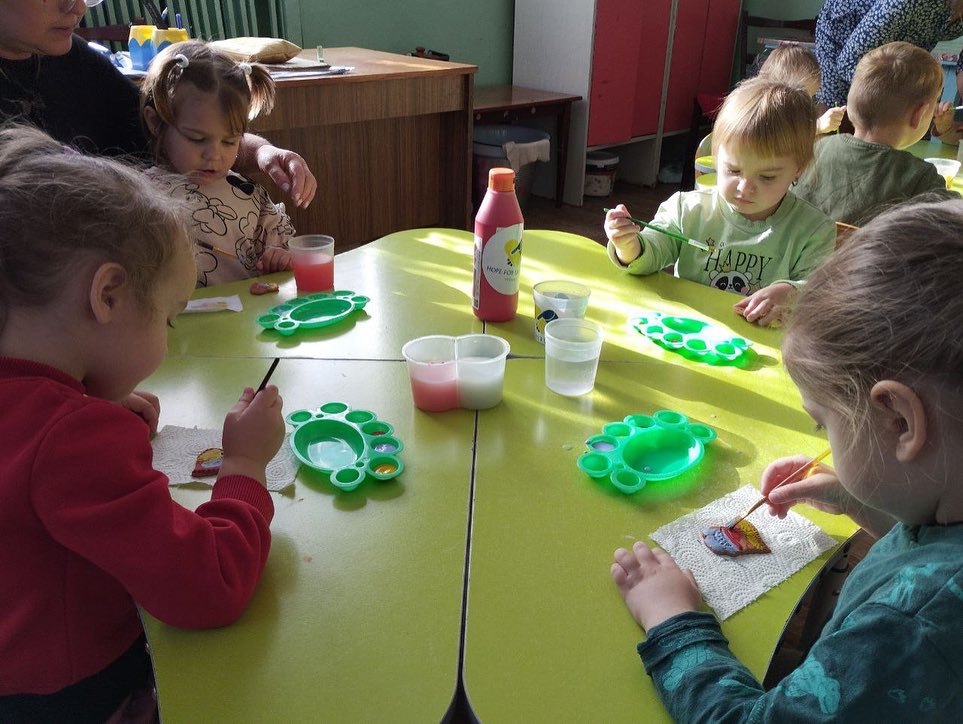 A group of children are sitting at a table and making crafts.