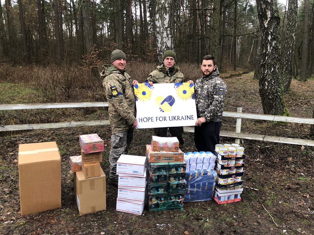 A group of men posing with boxes in the woods.