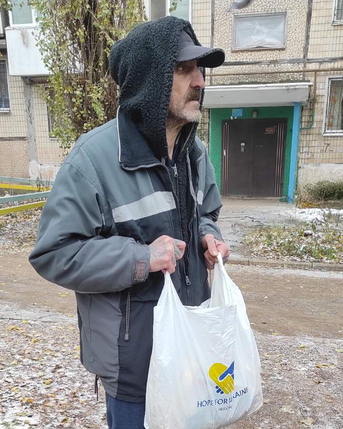 A man in a hoodie holding a plastic bag.