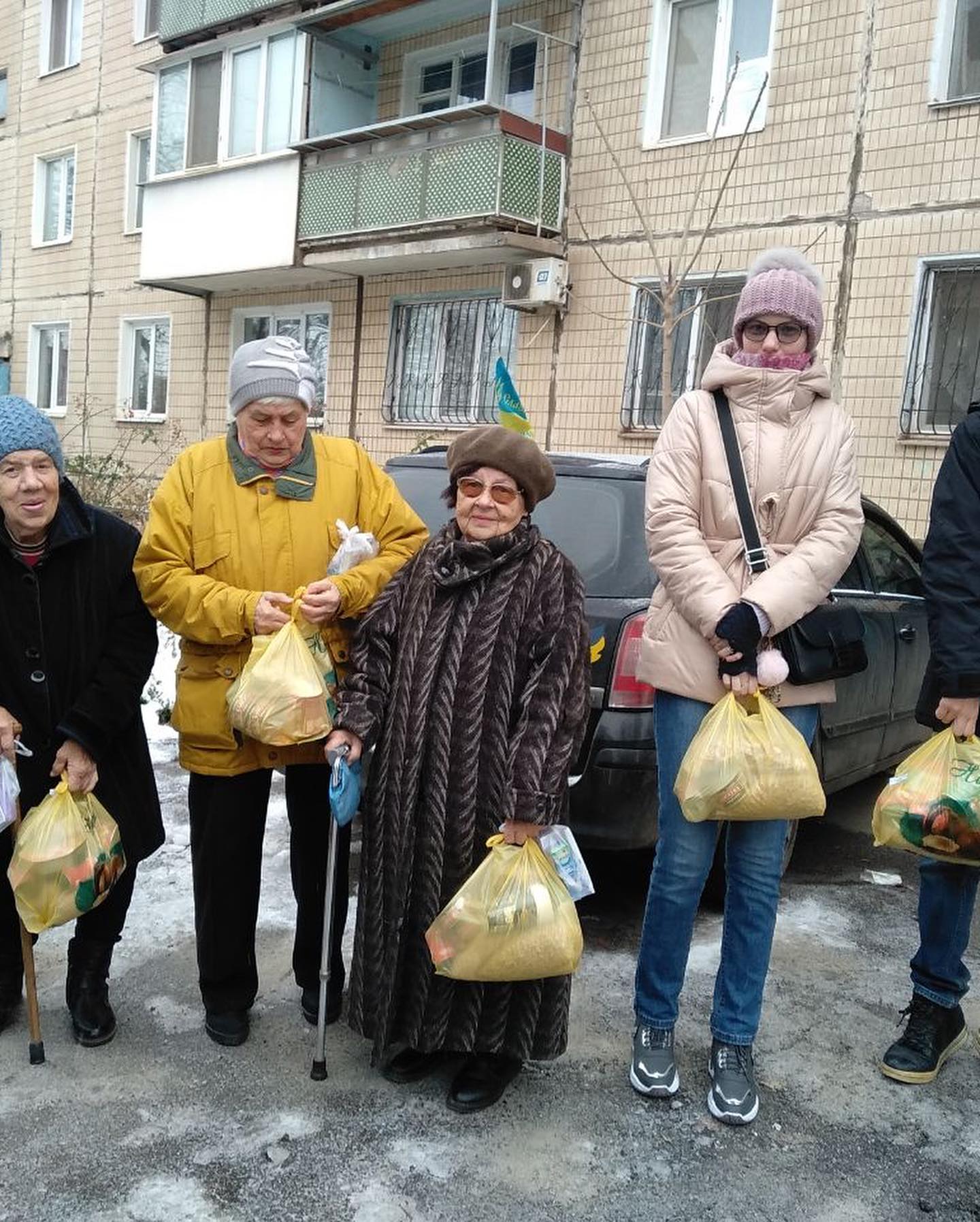 A group of people holding bags of food in front of a building.