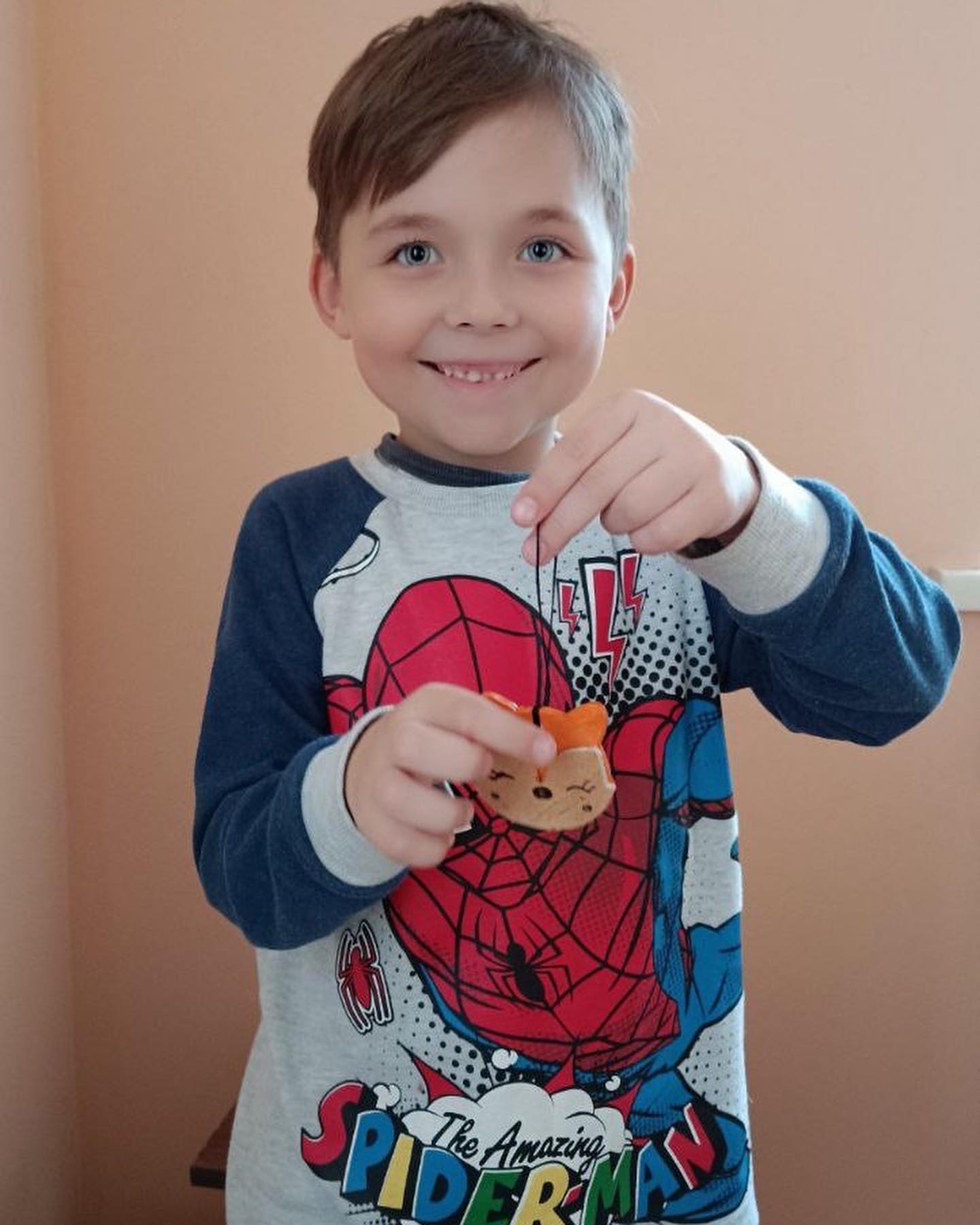 A young boy holding a spiderman cookie.