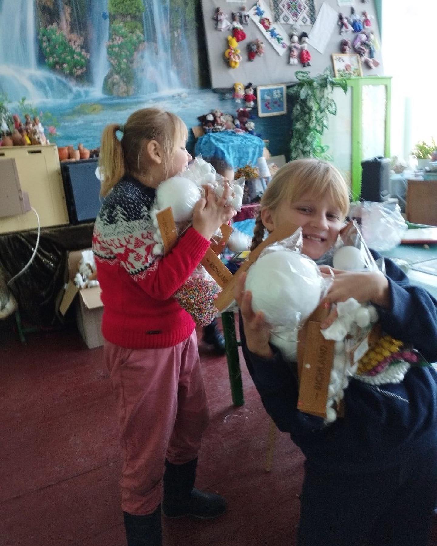 Two girls playing with stuffed animals in a room.