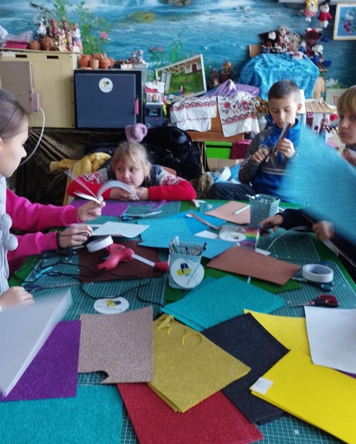 A group of children are sitting around a table making crafts.