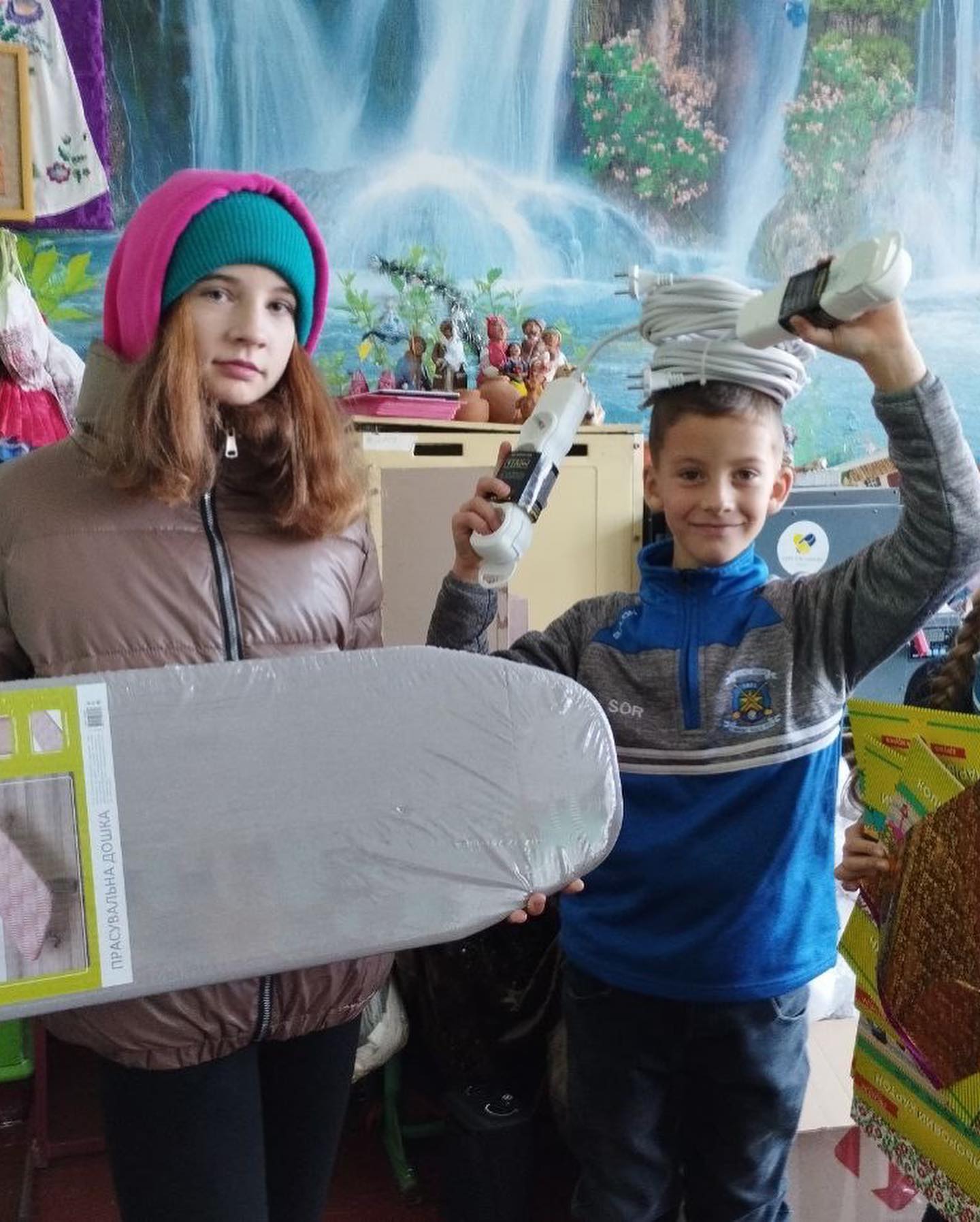 Two children holding skateboards in a room.