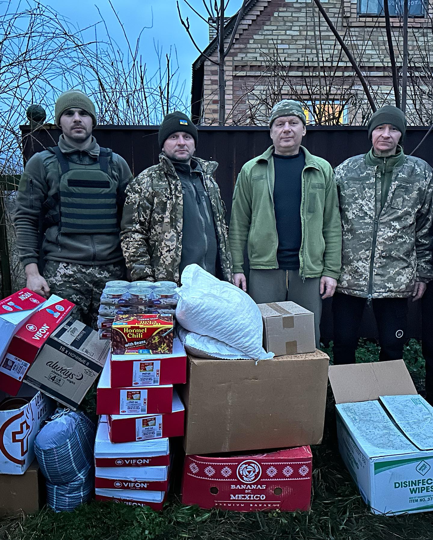 A group of men standing next to boxes of food.