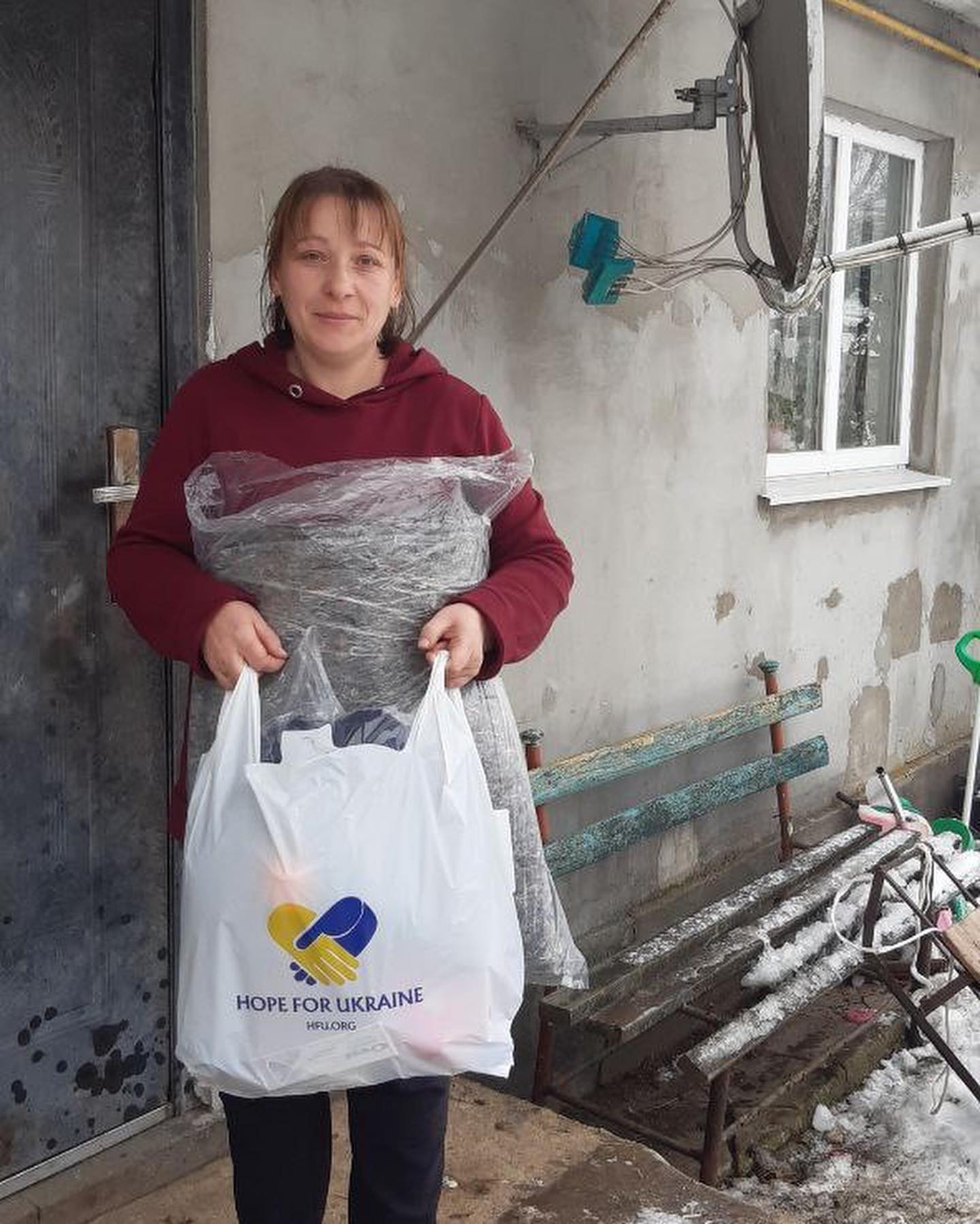 A woman holding a shopping bag in front of a house.