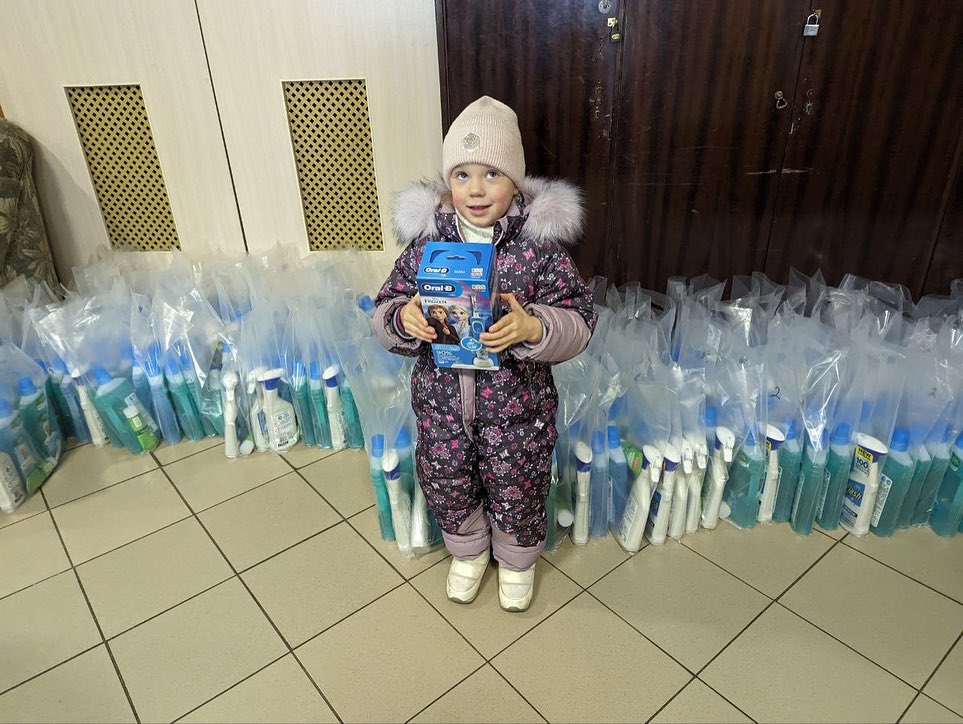 A young girl standing in front of bags of toiletries.