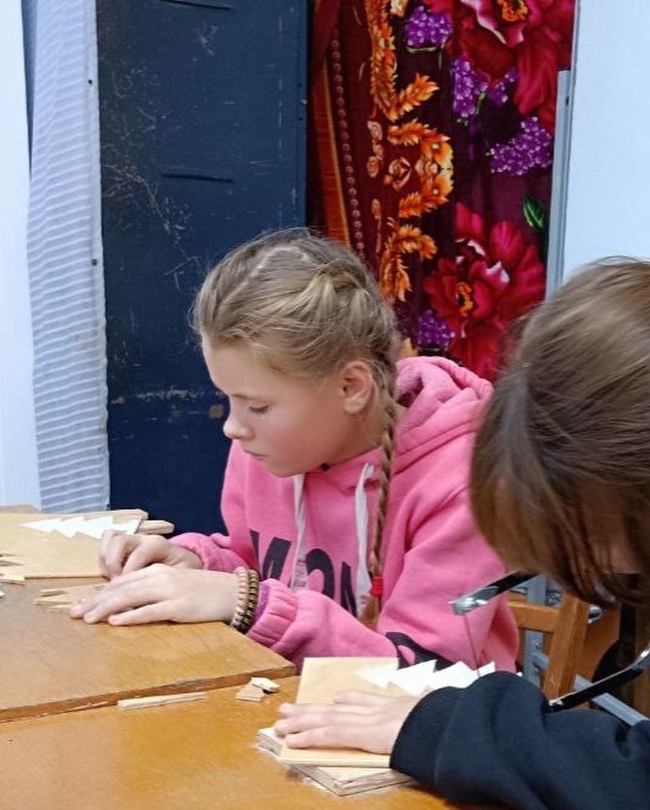 Two girls working at a table in a classroom.