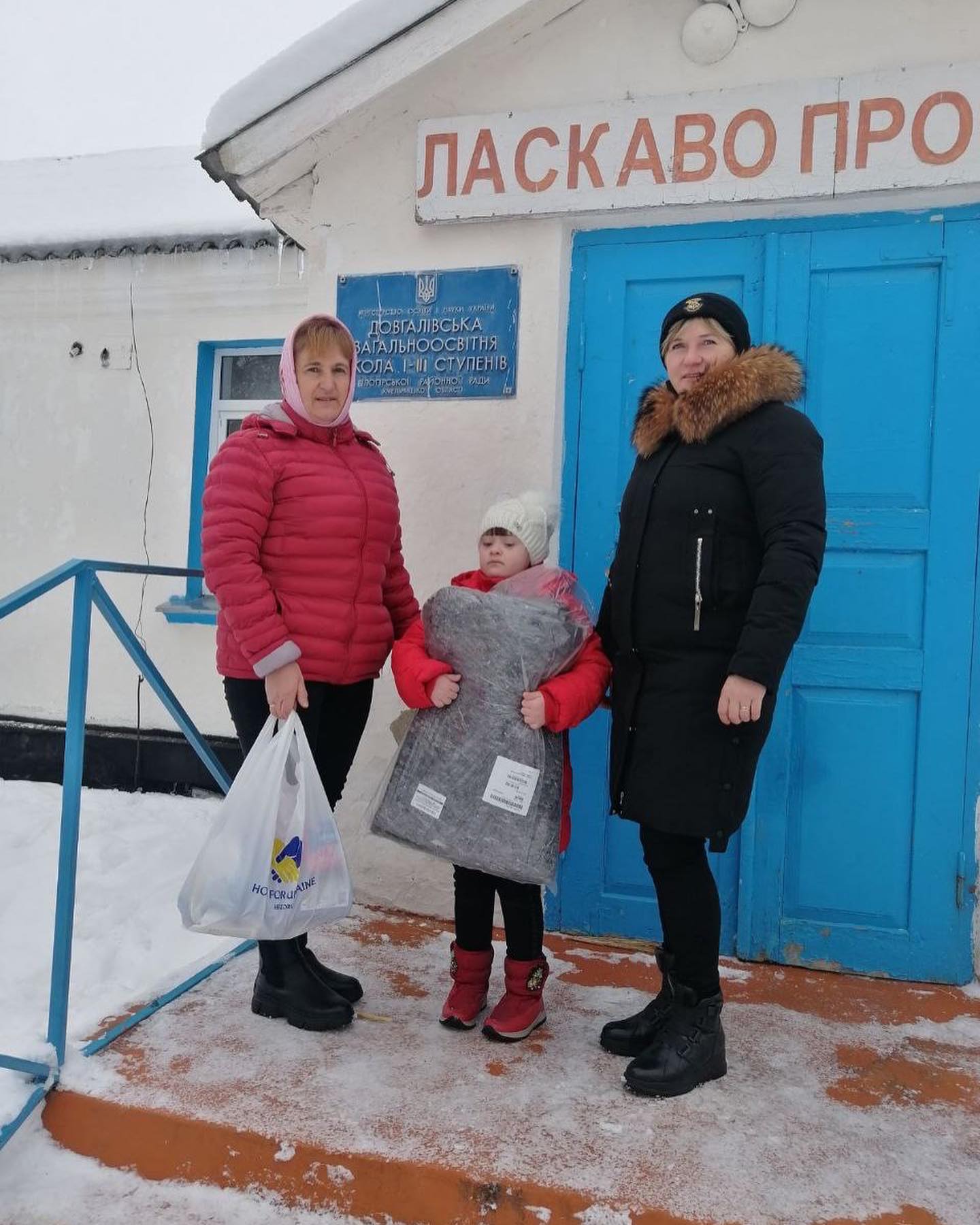 Three women and a child standing in front of a building.