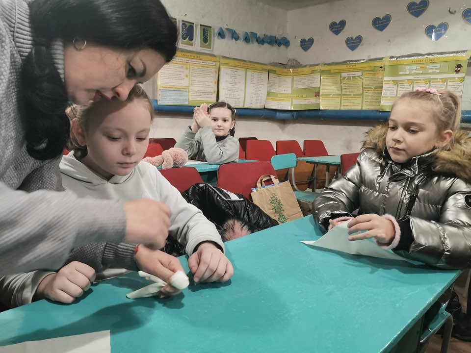 A group of children at a table with a teacher.