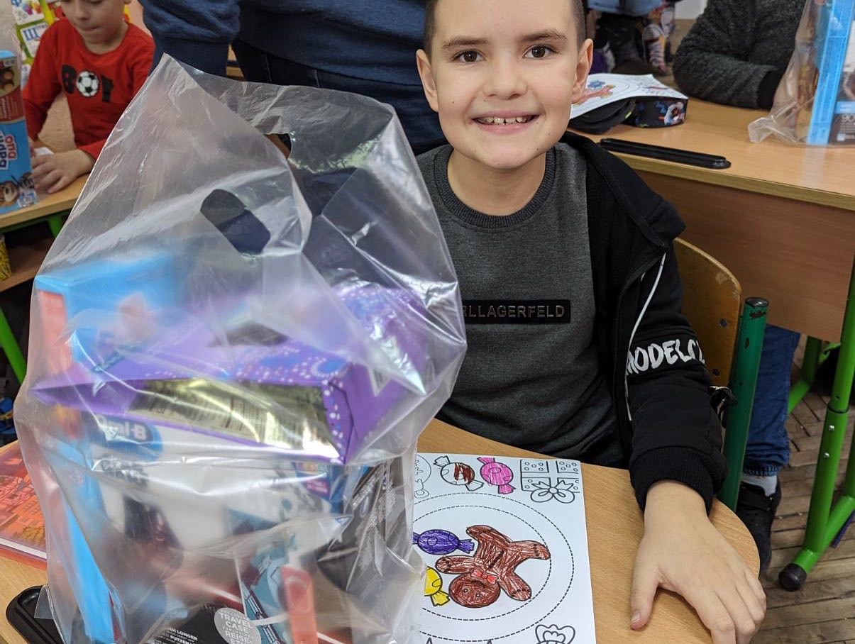 A boy sitting at a table with a bag of toys.