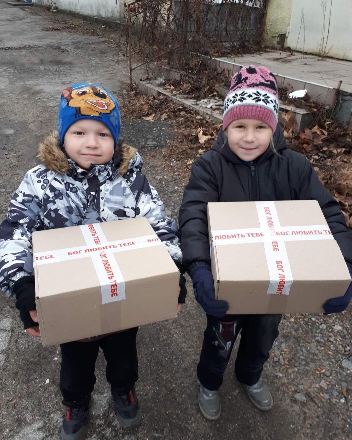Two boys holding boxes with labels on them.