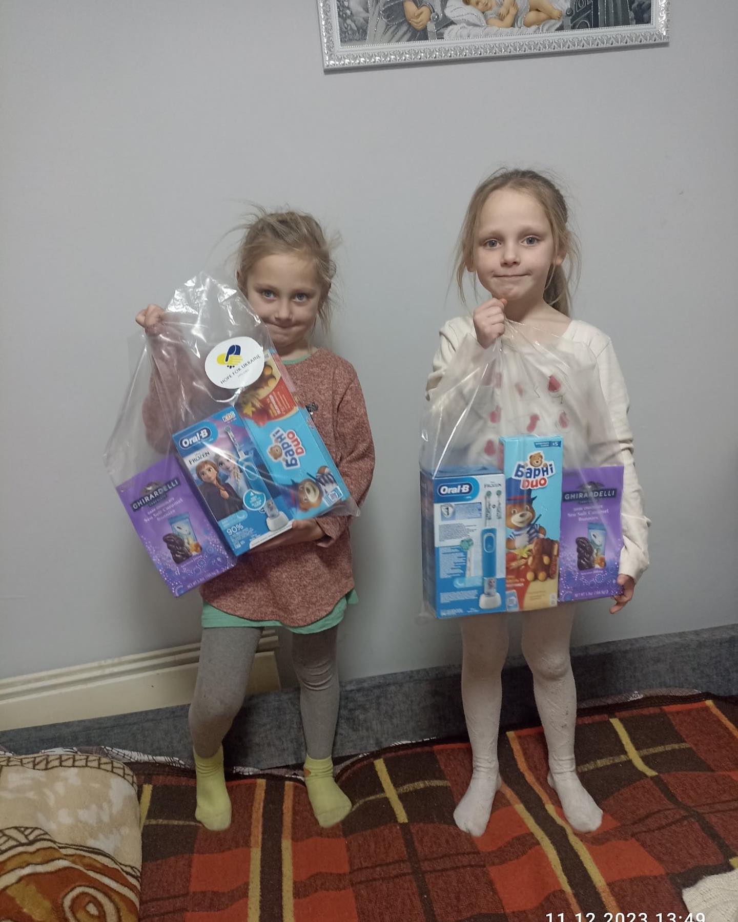 Two young girls holding bags of food and toys.