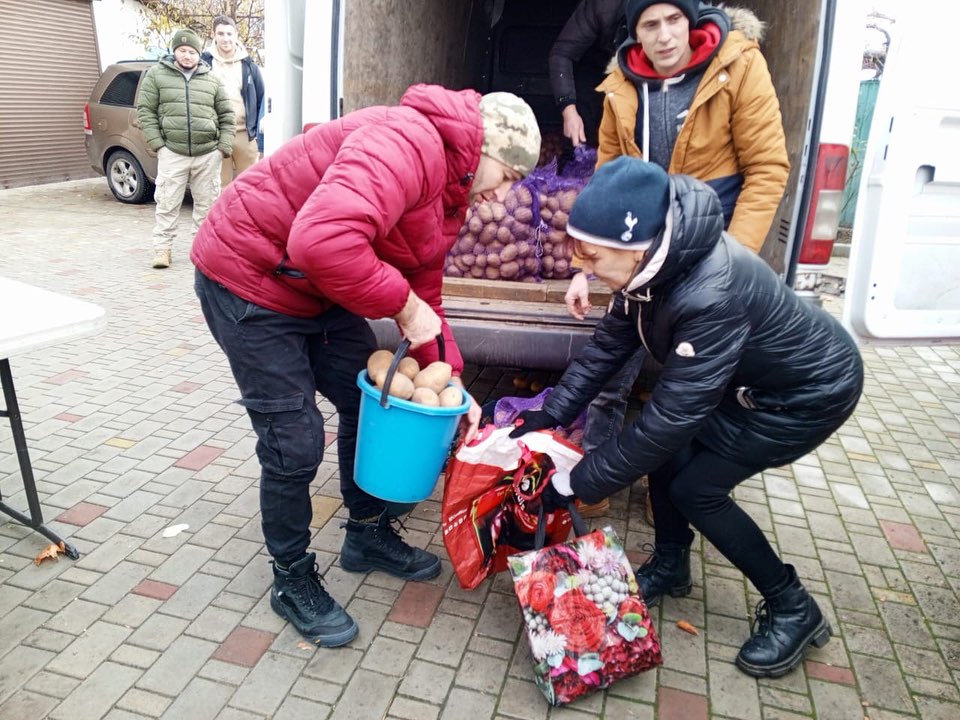 A group of people unloading potatoes from a truck.