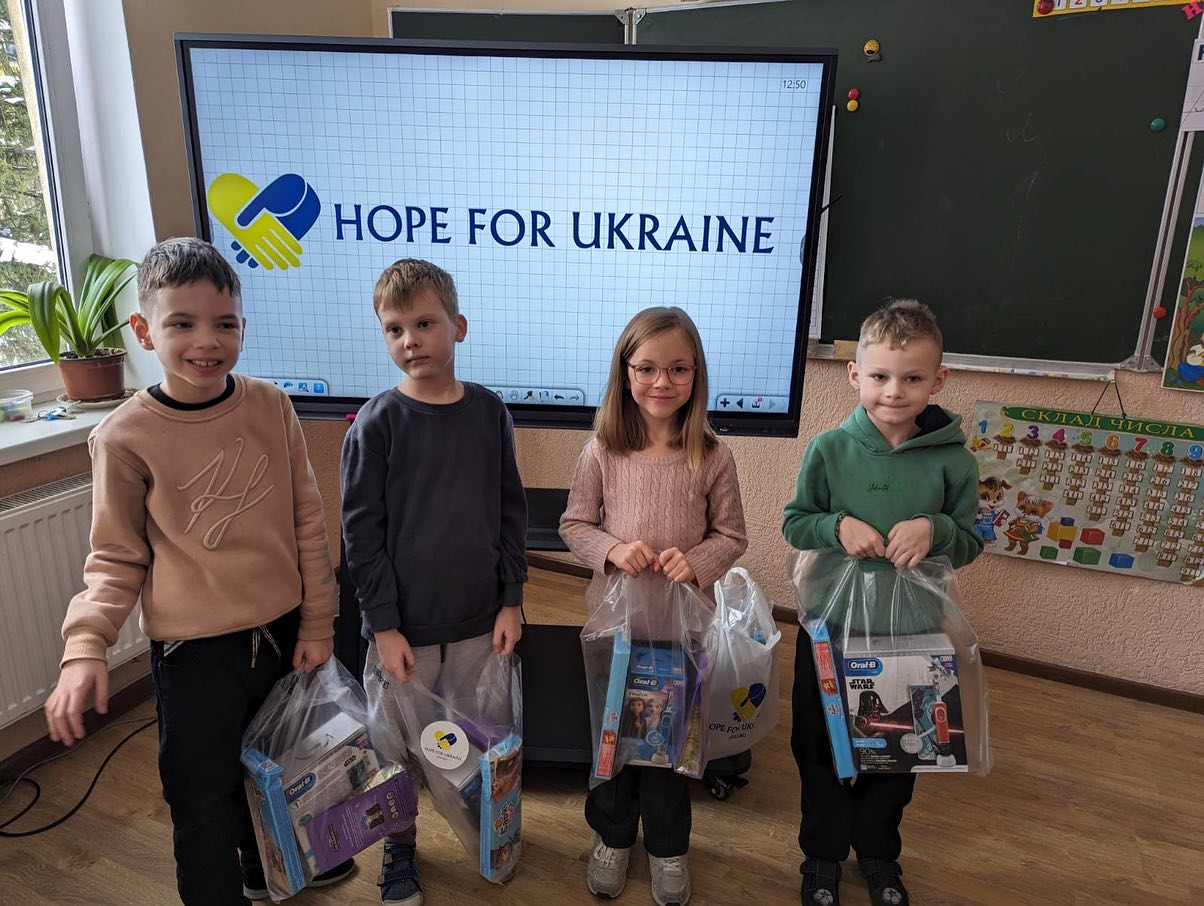Four children holding bags with the word hope for ukraine.