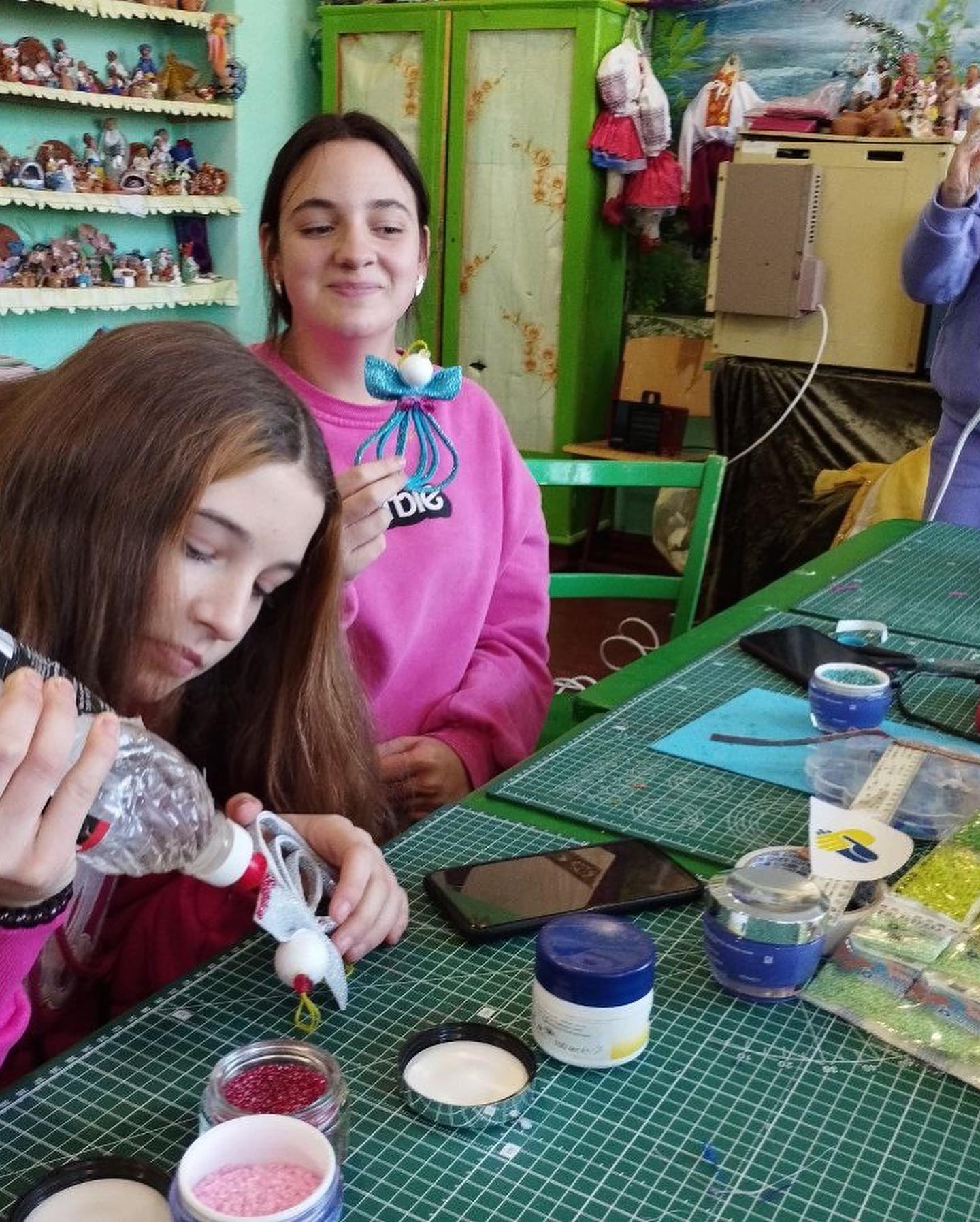 A group of girls are sitting at a table making crafts.