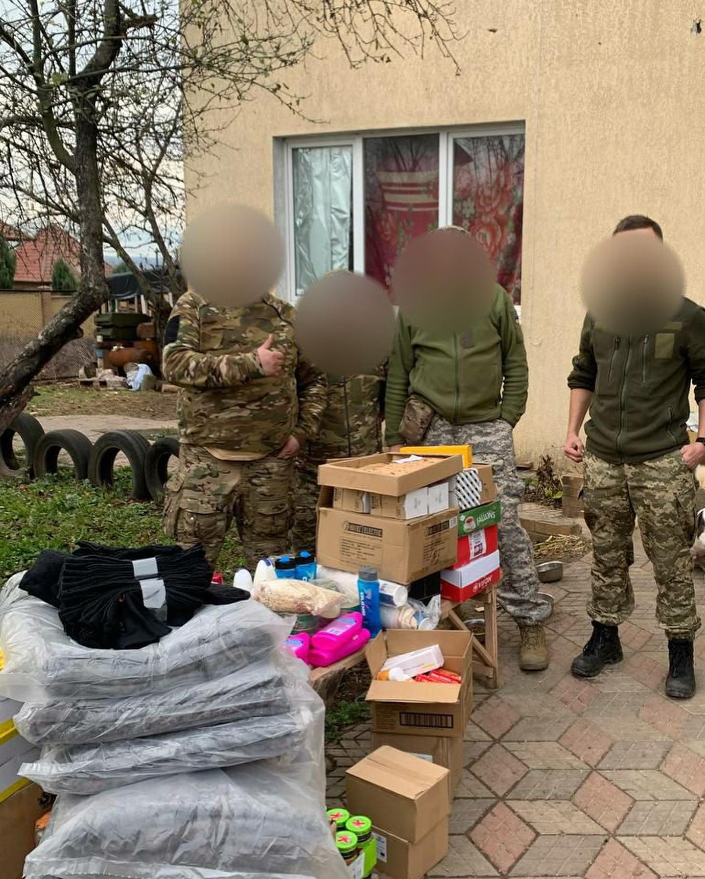 A group of soldiers standing in front of a house with boxes.