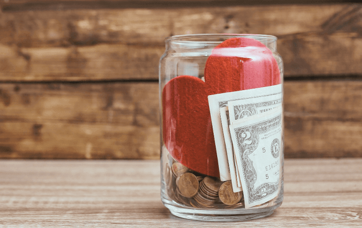 A glass jar filled with money and a red heart.