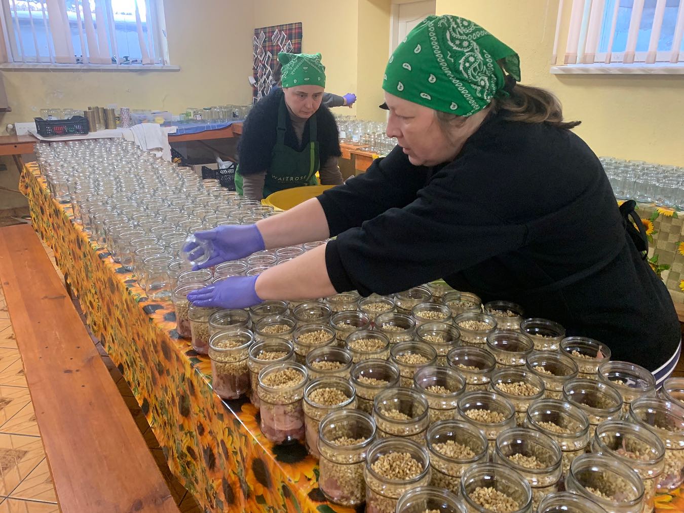 Two women are filling jars with seeds.