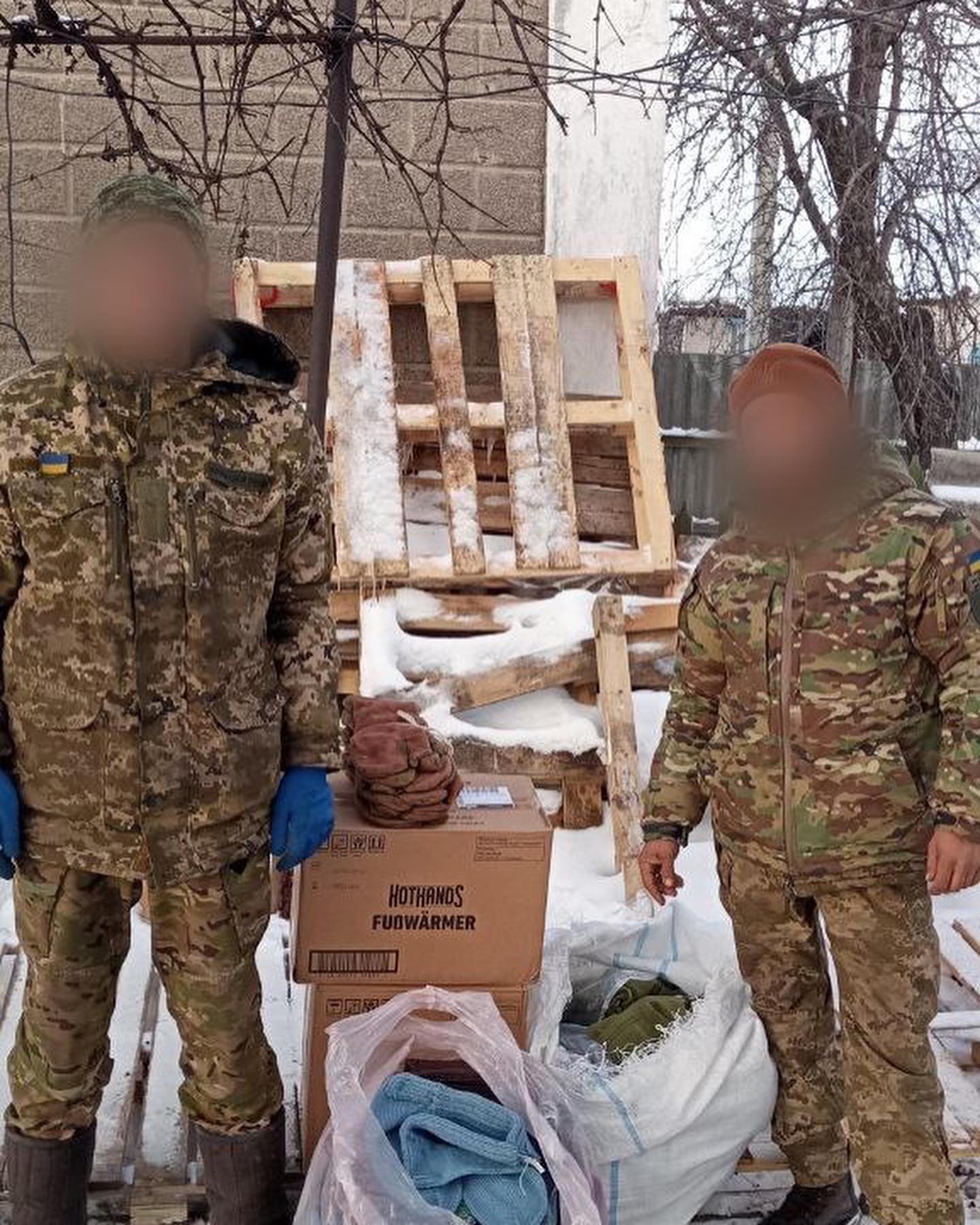 Two men in military uniforms standing next to boxes.