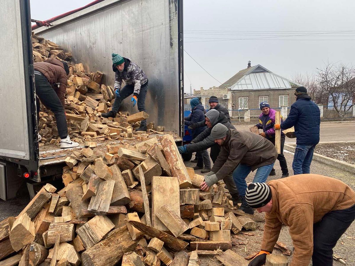 A group of people loading wood into a truck.