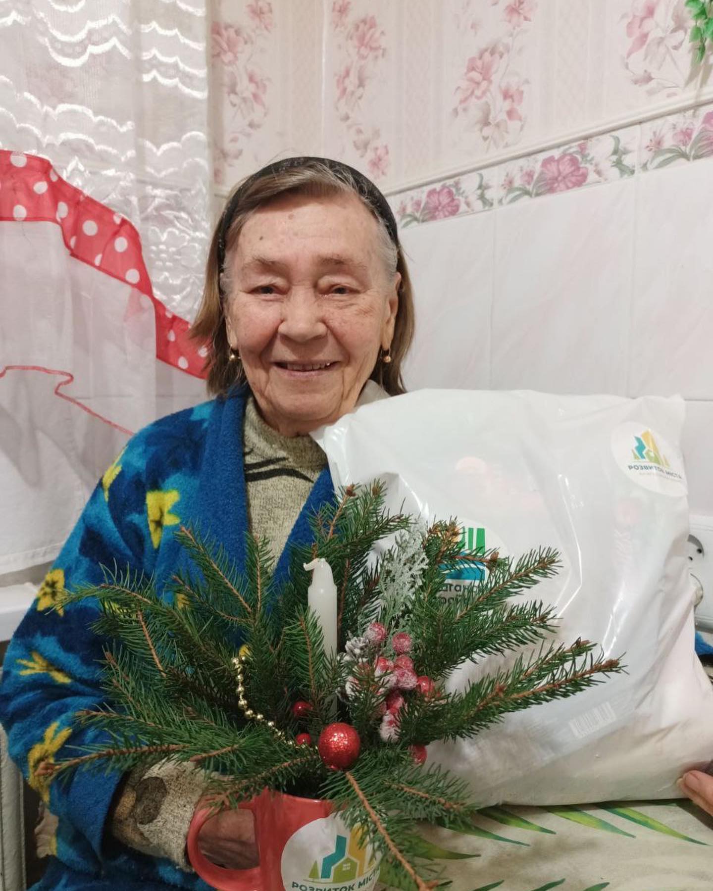 A woman holding a christmas tree and a bag.