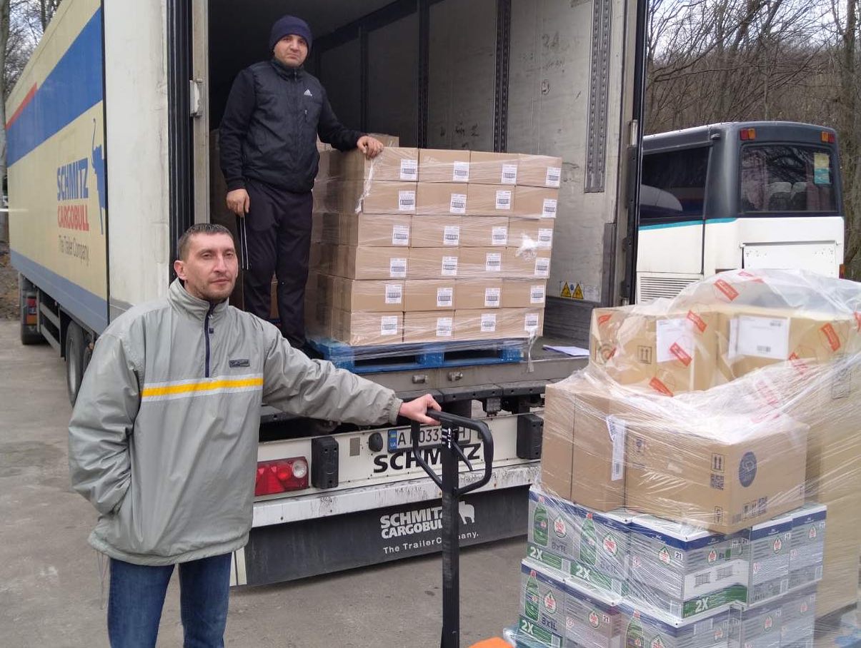 Two men standing next to a truck full of boxes.
