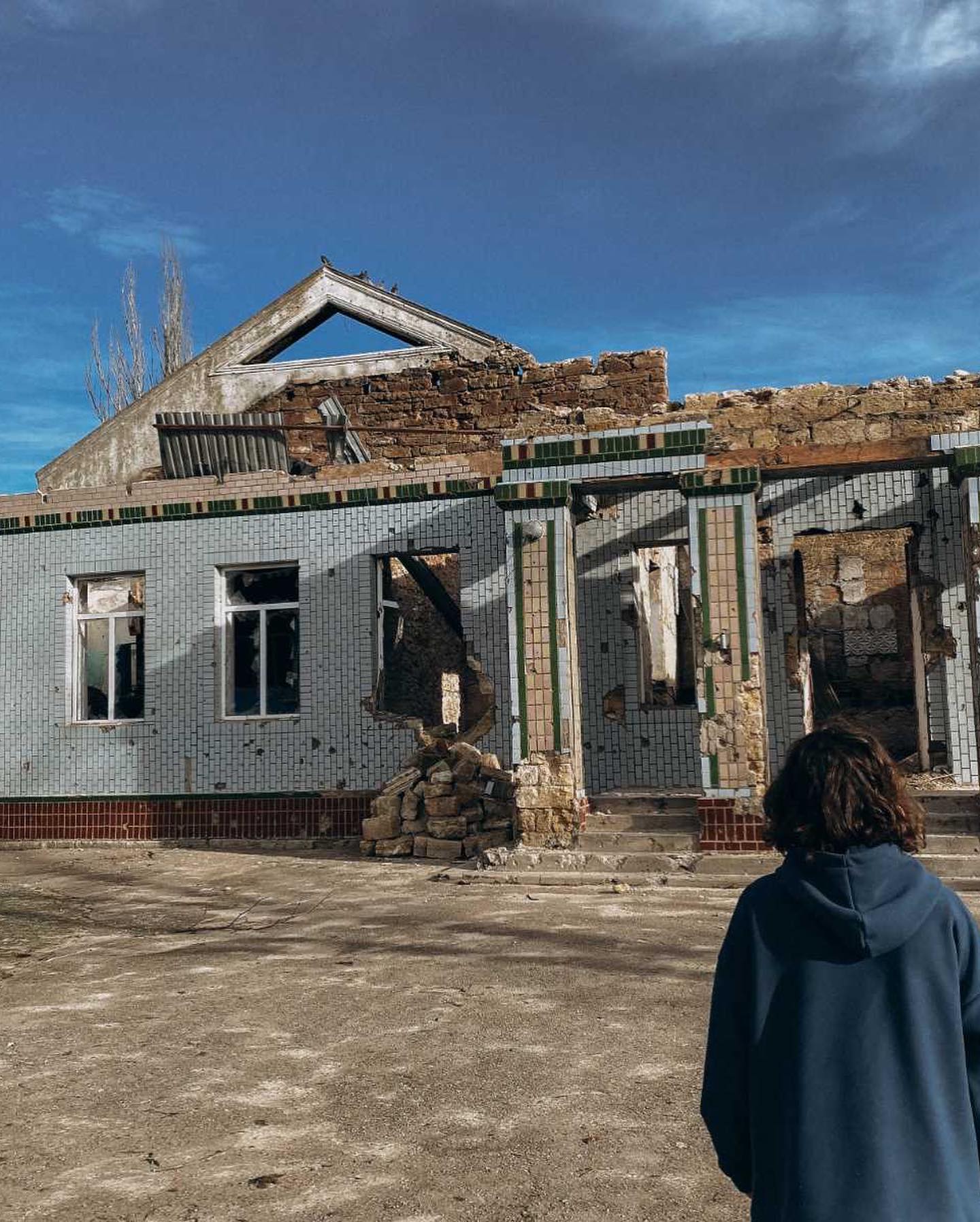 A man is standing in front of a building that has been destroyed.