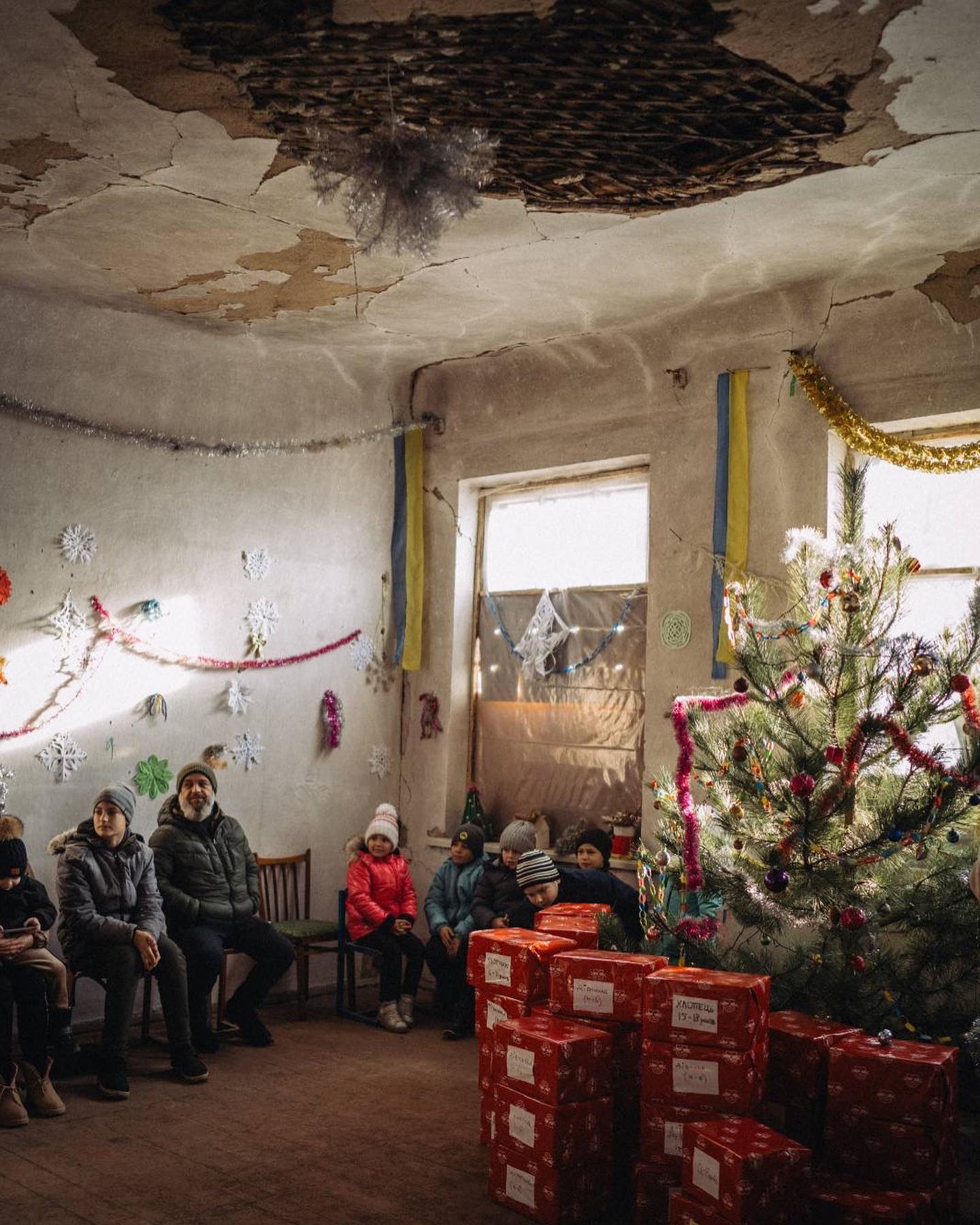 A group of people sitting around a christmas tree in a room.