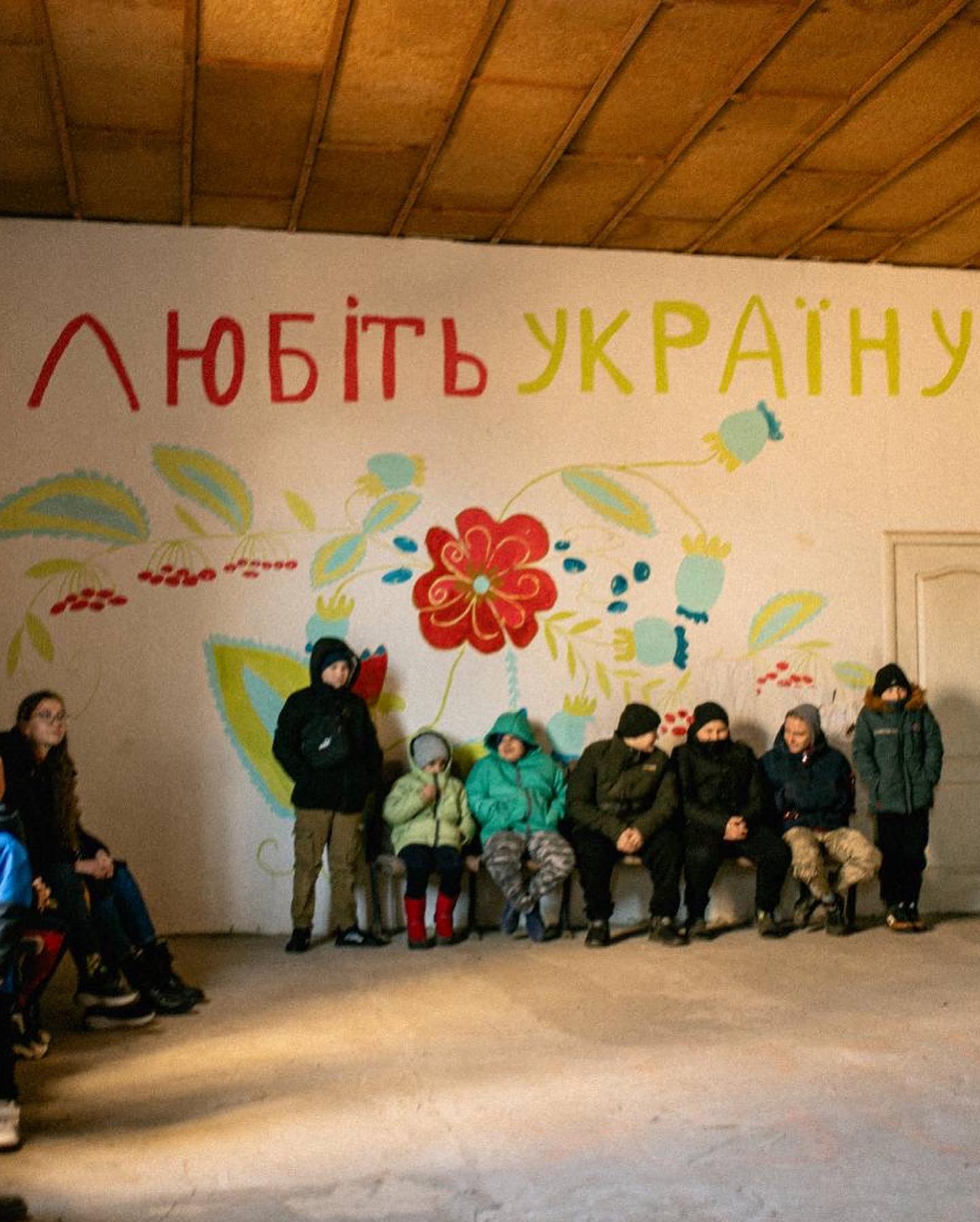 A group of people sitting in front of a painted wall.