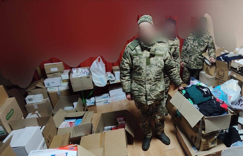 A group of soldiers standing in a room full of boxes.