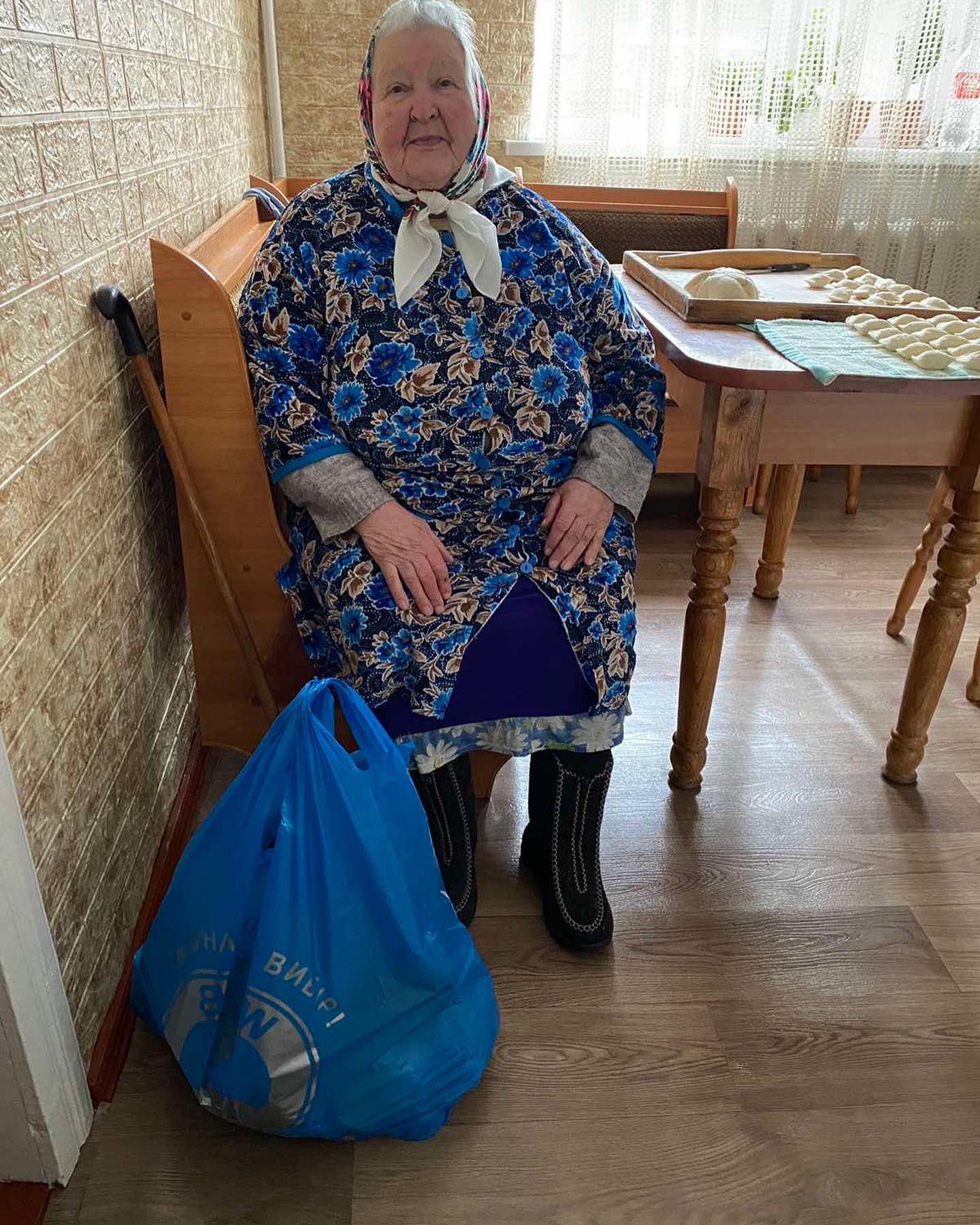 A woman sitting on a chair with a blue bag.
