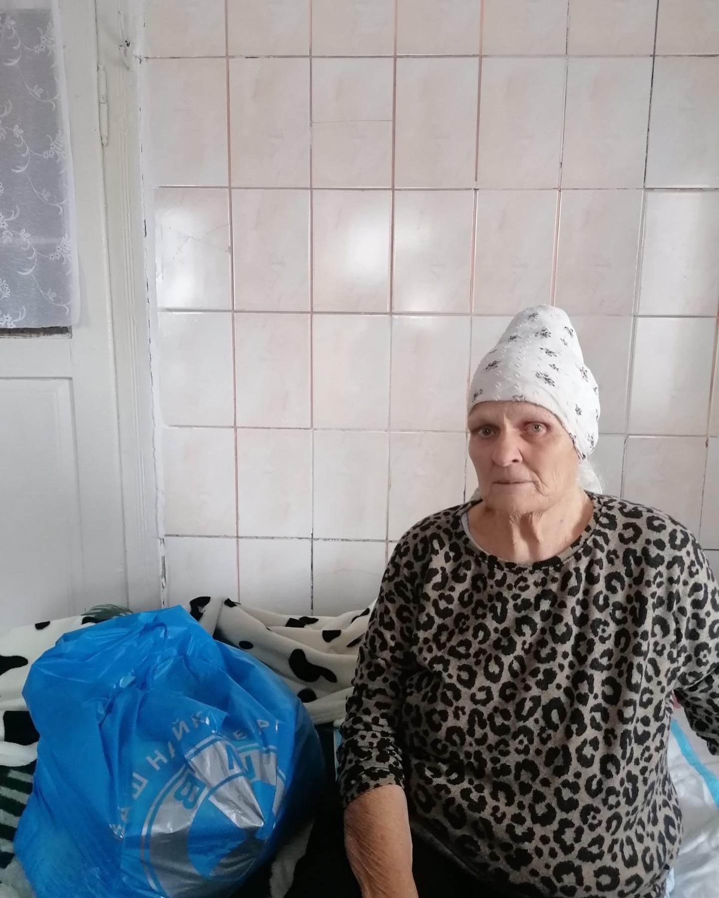 A woman sitting on a bed with a bag on her head.