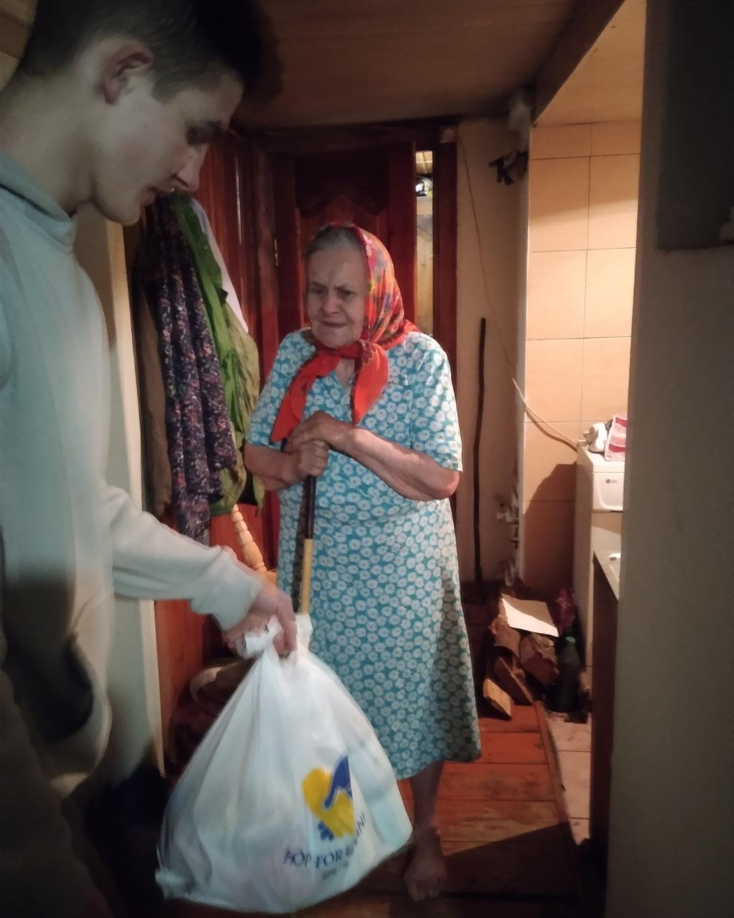 A man and a woman standing in a kitchen with a bag.