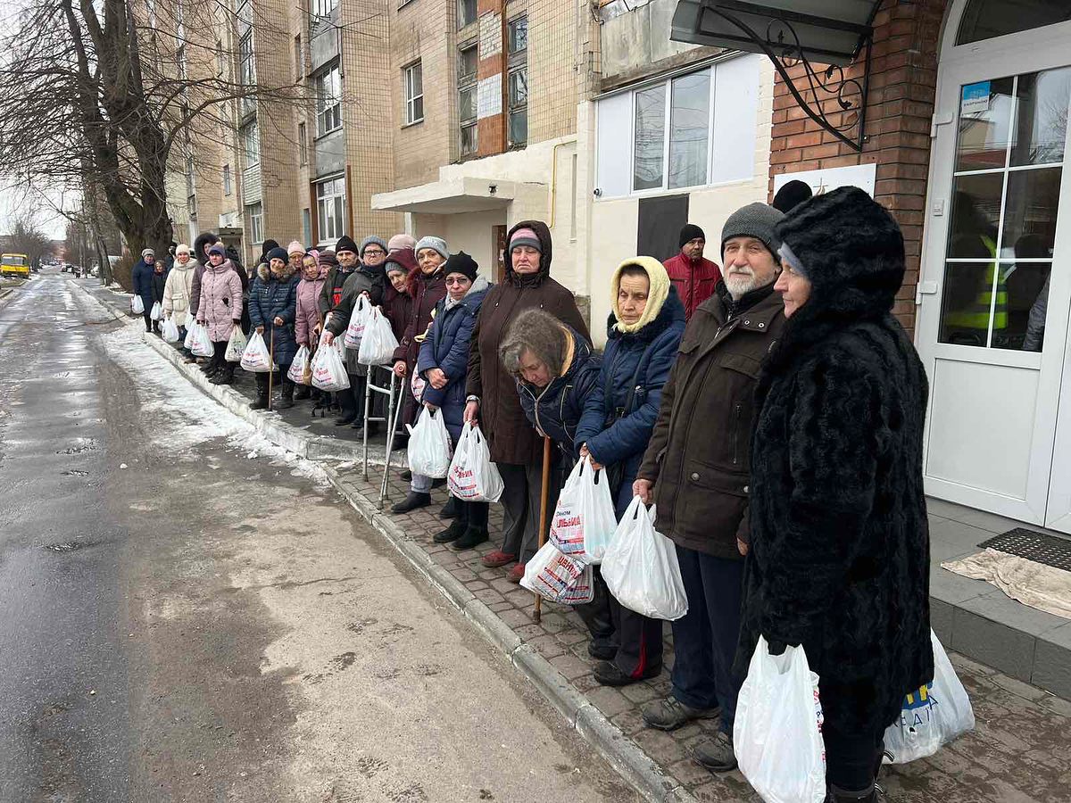 A group of people standing in a line with bags.