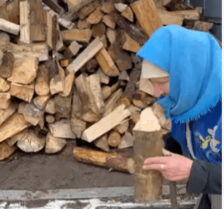 A woman wearing a blue hat is holding a pile of wood.