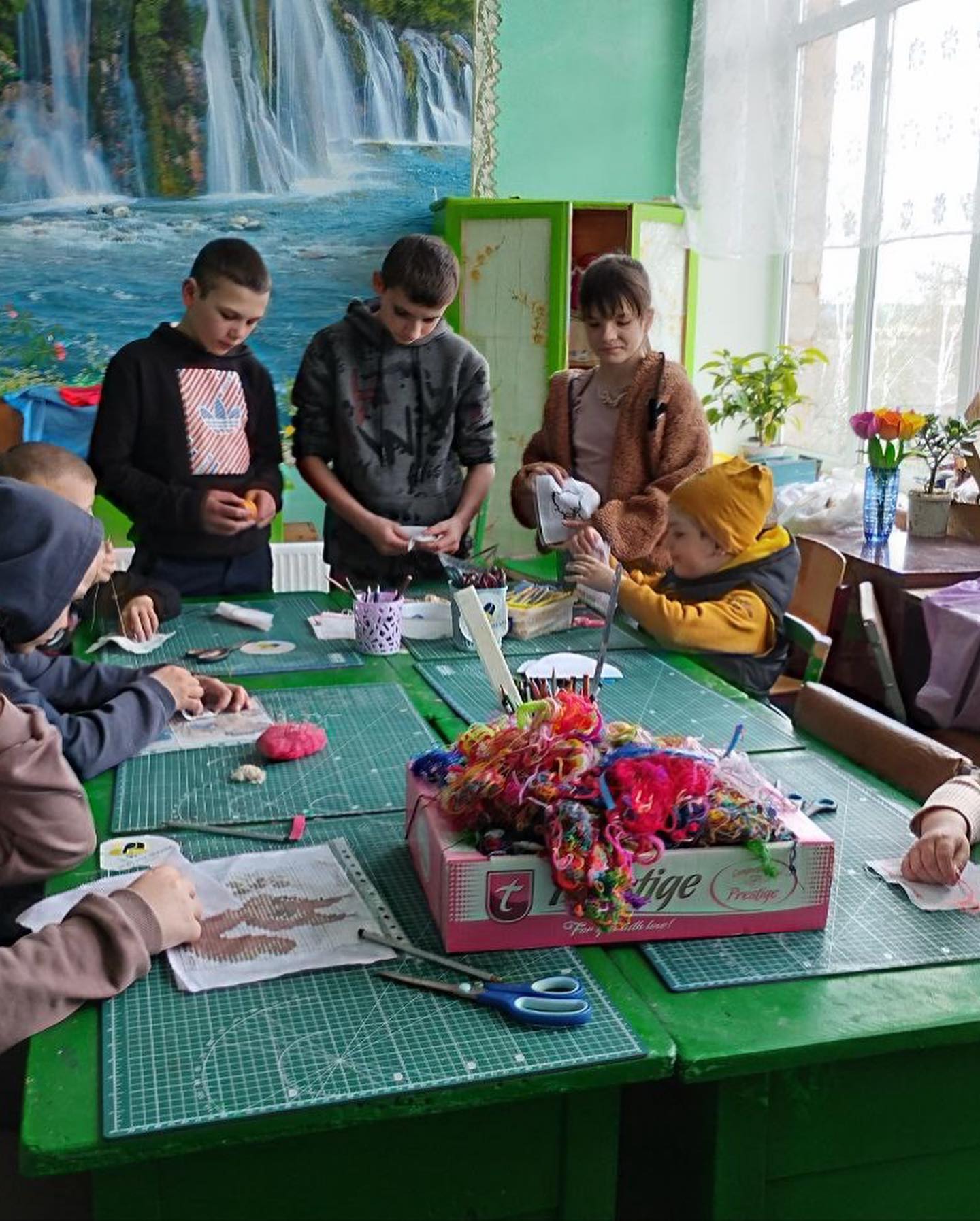 Children engaged in a craft activity around a table in a classroom with a "Hope for Ukraine" poster in the background.