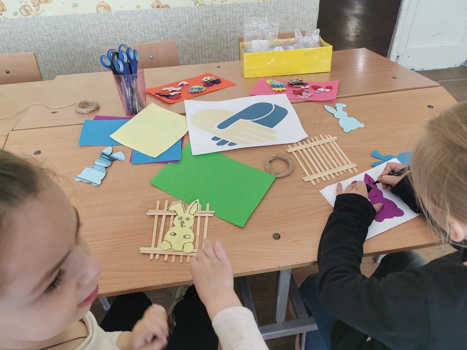 Children engaged in crafts at a table scattered with colorful papers, glue, and scissors in a classroom in the Donetsk region.