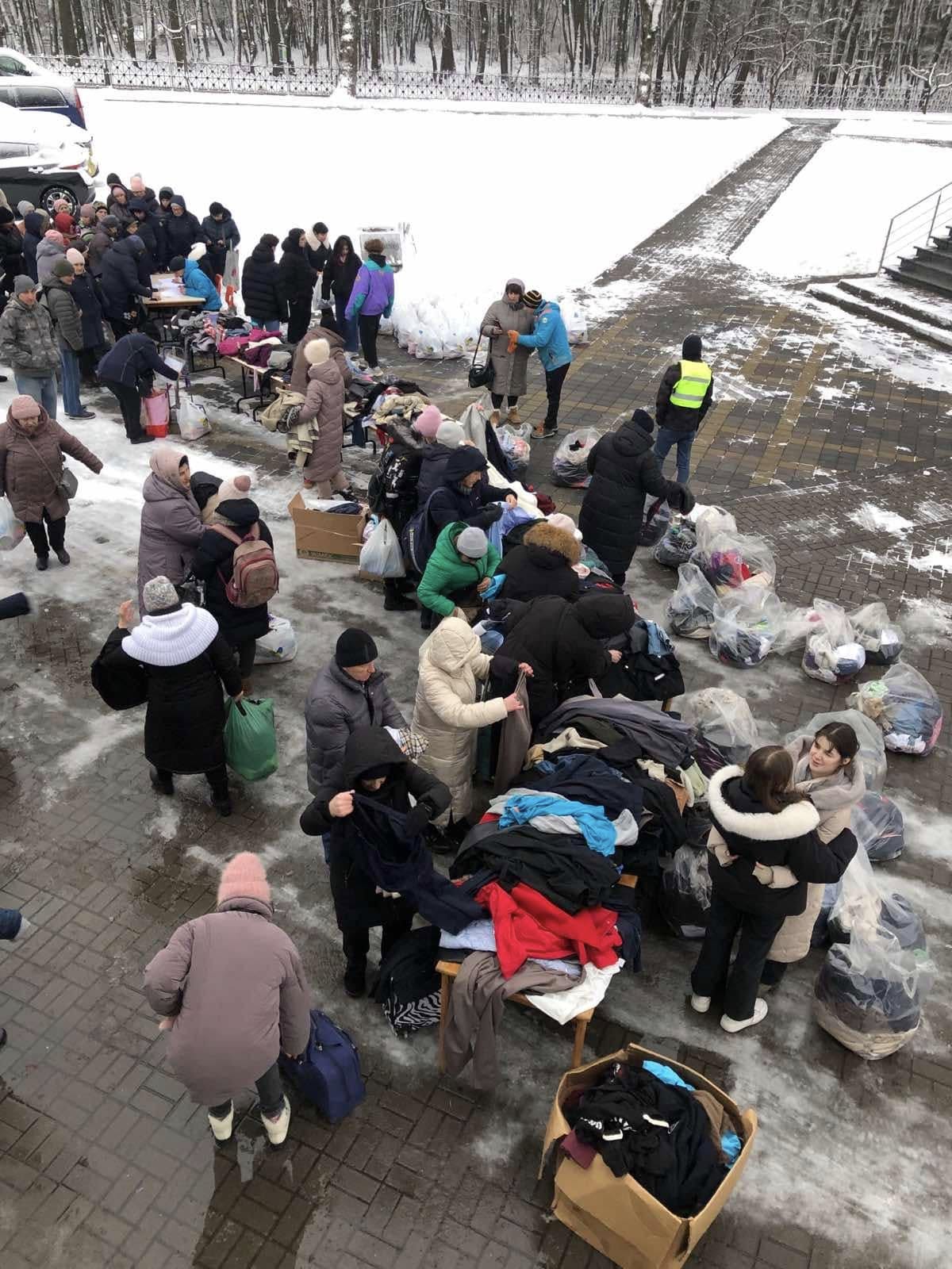 People providing family support to Kriviy Rih sort and distribute clothing donations outdoors on a snow-covered day.