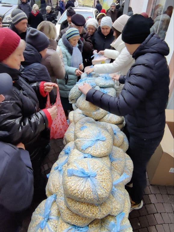 A group of people is spreading holiday joy by distributing bags of food on a bustling street.