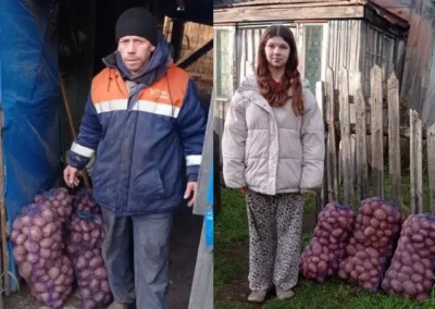 donate to ukraine - A ukrainian man and a woman stand outdoors beside large sacks filled with potatoes; the man is near a shed, and the woman is by a wooden fence.