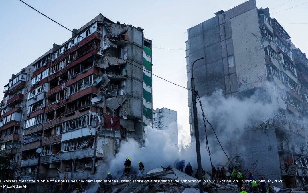 Rescue workers clear rubble from a heavily damaged residential building after a Russian strike in Kyiv, Ukraine, with smoke rising from the debris.