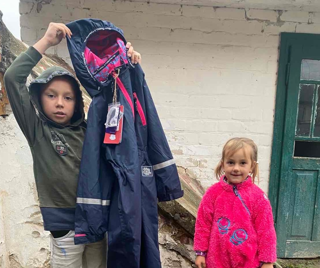 children holding up clothing that they received to stay warm