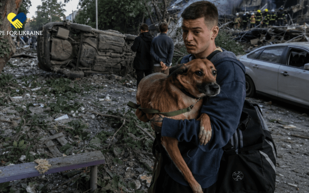 A man carries a frightened dog through smoke, rubble, and debris after an attack in Ukraine.