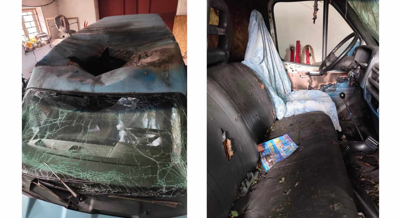 A vehicle with a shattered windshield and a large hole in the roof, believed to be linked to an incident where a humanitarian volunteer was killed in Ukraine. The interior shows damaged seats, debris, and a magazine on the torn bench seat.