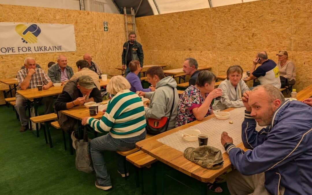 People gathered in a tent for a community meal supported by Hope For Ukraine.