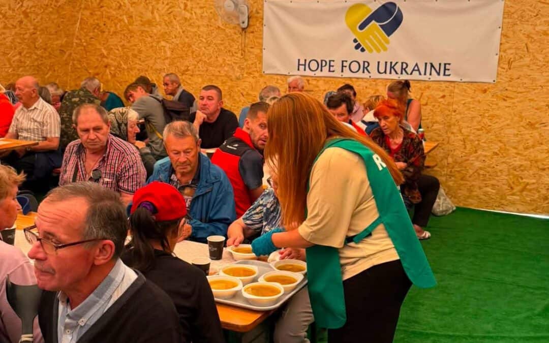 Volunteer serving food to people at a Hope For Ukraine event.