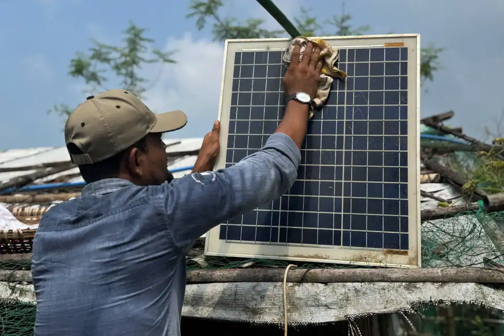 Mohammed Saber cleans a portable solar panel in Teknaf, Bangladesh, as photographed for the Associated Press